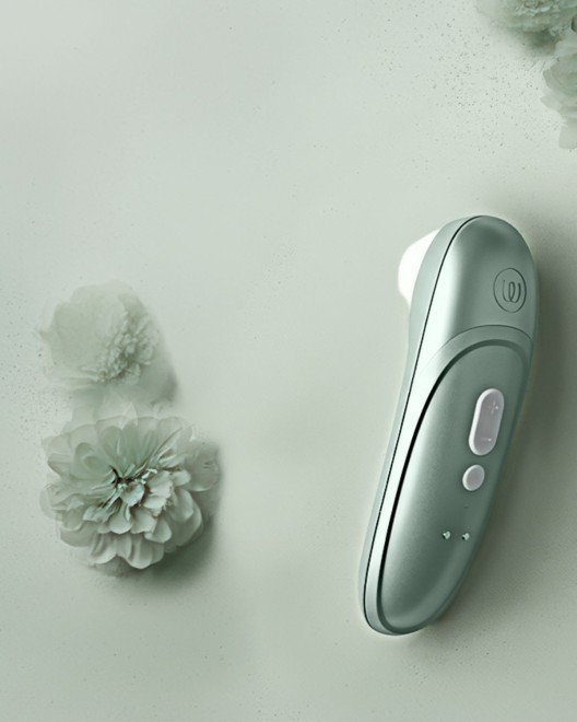 stimulateur clitoridien à air pulsé Womanizer Pro, vert sauge, à côté d'une fleur