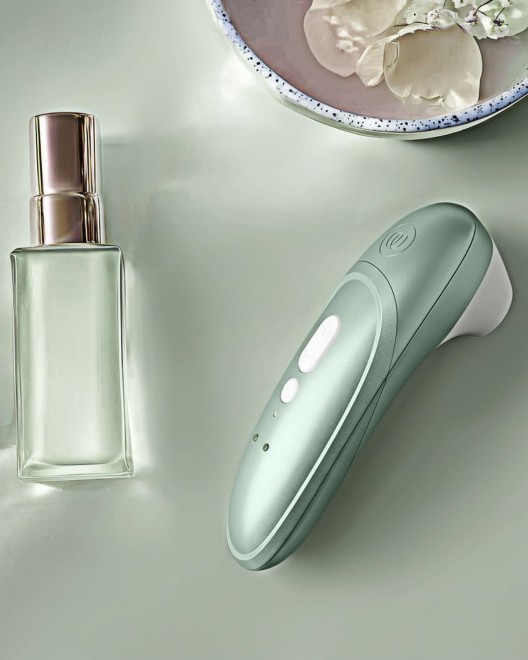 stimulateur clitoridien à air pulsé Womanizer Pro, vert sauge, à côté d'un parfum