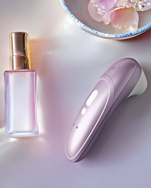 stimulateur clitoridien à air pulsé Womanizer Pro, lilas, à côté d'un parfum