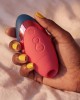 Womanizer next liberty bleu et bordeaux dans une main avec du vernis